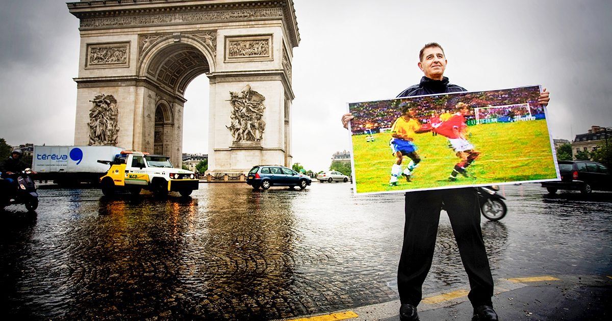National Soccer Hall of Famer Esse Baharmast poses with an image of a famous World Cup call that he made as a referee.