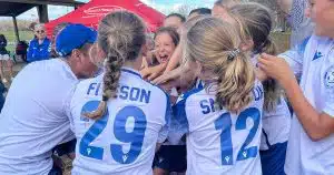 A group of youth soccer players celebrate after a win.